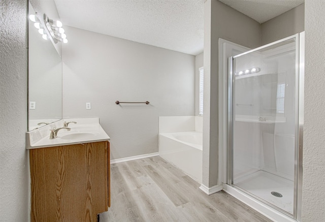 bathroom with hardwood / wood-style floors, vanity, a textured ceiling, and independent shower and bath