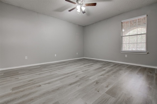 spare room with light wood-type flooring, a textured ceiling, and ceiling fan