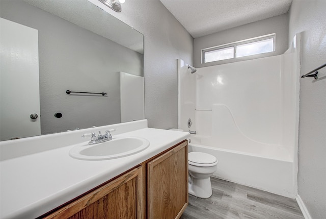 full bathroom featuring toilet, hardwood / wood-style floors, a textured ceiling, vanity, and bathtub / shower combination