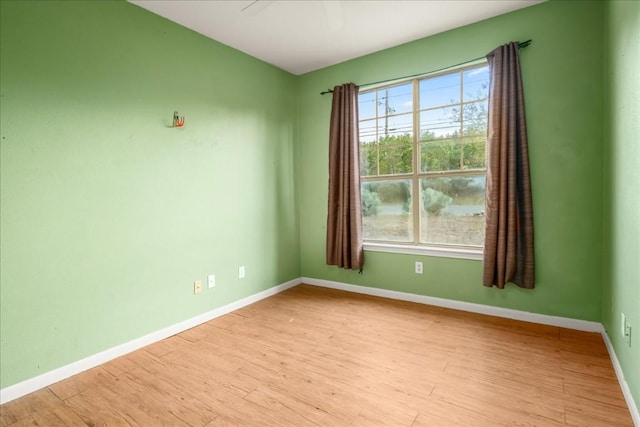 empty room with baseboards, a ceiling fan, light wood-style flooring, and a healthy amount of sunlight