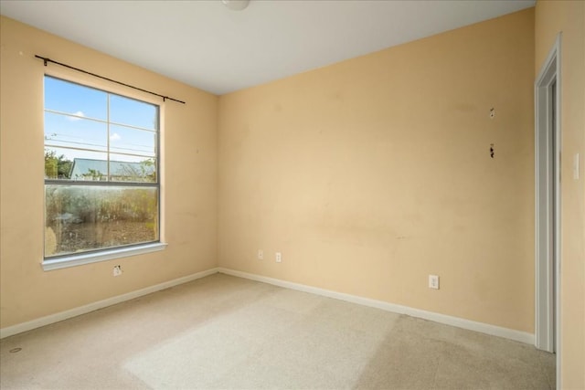 unfurnished room with baseboards and light colored carpet