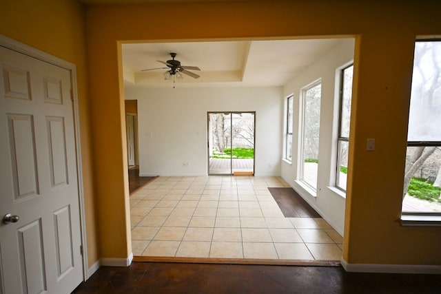 interior space with a raised ceiling and a ceiling fan