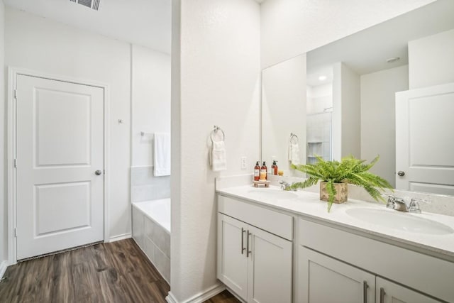 bathroom featuring vanity, hardwood / wood-style flooring, and tiled tub