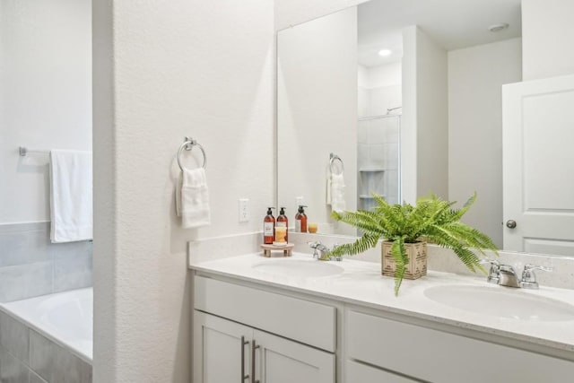 bathroom featuring vanity and a relaxing tiled tub