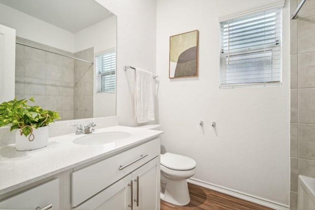 bathroom featuring a wealth of natural light, vanity, wood-type flooring, and toilet