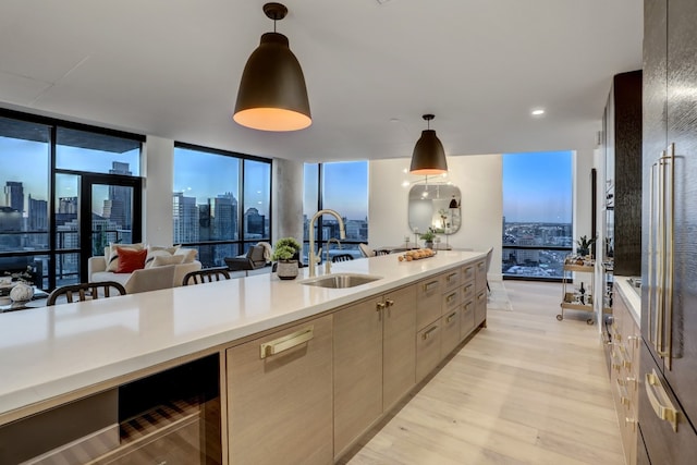 kitchen featuring expansive windows, light wood-type flooring, sink, and pendant lighting