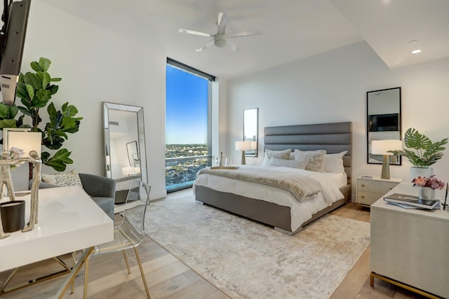 bedroom with ceiling fan, a wall of windows, and light hardwood / wood-style flooring