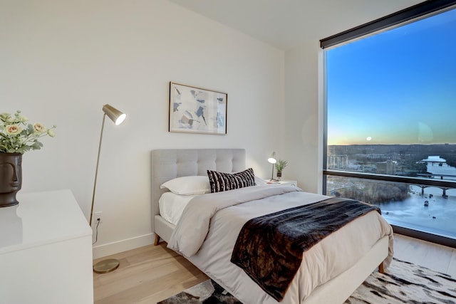 bedroom with expansive windows and light wood-type flooring