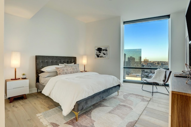 bedroom featuring a wall of windows and light wood-type flooring