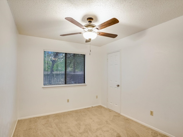 carpeted spare room featuring a textured ceiling and ceiling fan