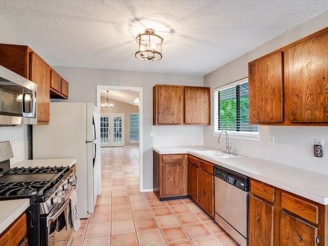 3606 Lovage Dr, Austin, TX 78727 - kitchen with appliances with stainless steel finishes, a chandelier, light countertops, brown cabinets, and a textured ceiling