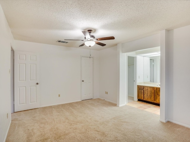 empty room with ceiling fan, a textured ceiling, and light carpet