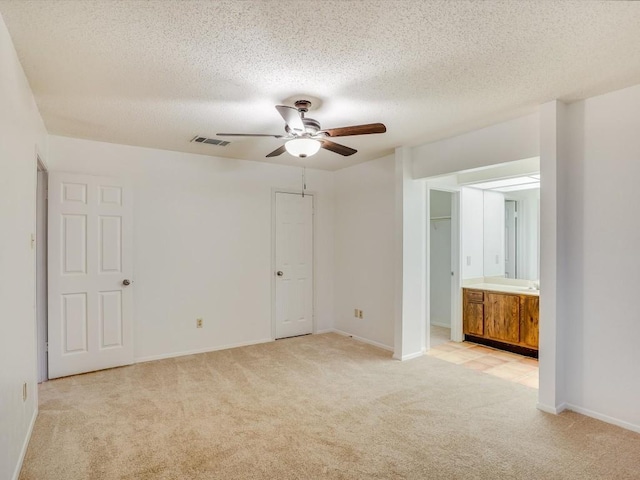 3606 Lovage Dr, Austin, TX 78727 - unfurnished bedroom featuring light carpet, a textured ceiling, ensuite bathroom, and a ceiling fan