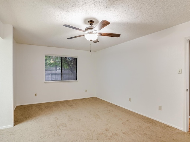 spare room with ceiling fan, light colored carpet, and a textured ceiling