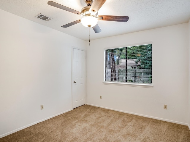 empty room featuring a textured ceiling, light carpet, and ceiling fan