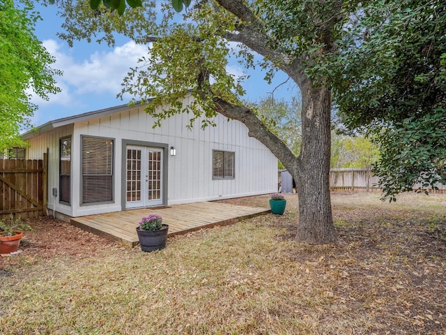 rear view of house featuring french doors, a wooden deck, and a lawn