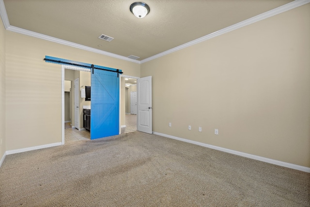 unfurnished bedroom with a textured ceiling, a barn door, light colored carpet, and ornamental molding