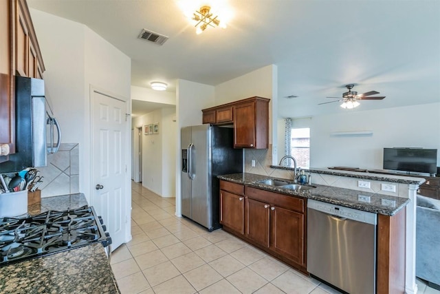 kitchen featuring ceiling fan, sink, dark stone countertops, light tile patterned floors, and appliances with stainless steel finishes