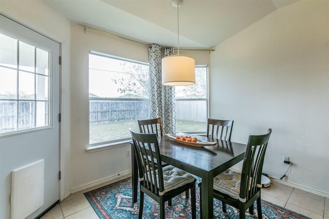 dining space featuring light tile patterned floors and vaulted ceiling