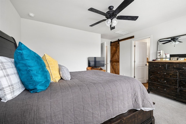 carpeted bedroom with a barn door and ceiling fan