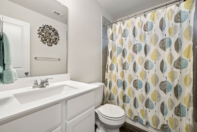 bathroom featuring walk in shower, vanity, and toilet