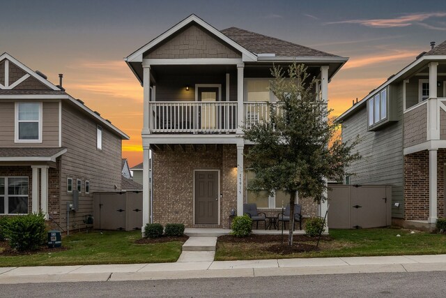 craftsman-style house with a lawn, a balcony, and a storage unit