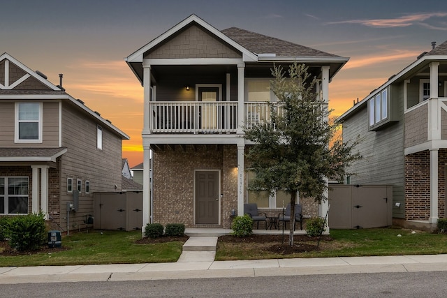 craftsman inspired home featuring a balcony and a lawn