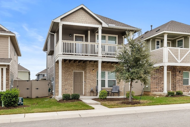 view of front of property with a balcony, a porch, and a front lawn