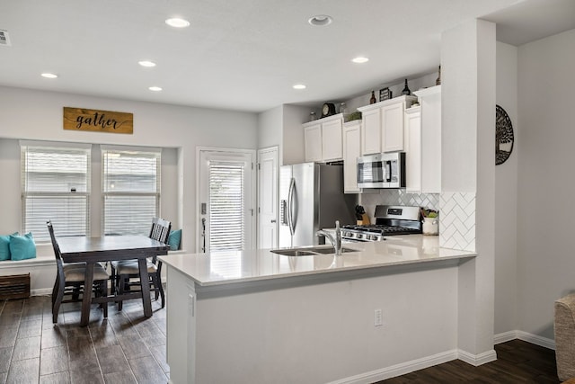 kitchen featuring dark wood-type flooring, sink, white cabinetry, appliances with stainless steel finishes, and kitchen peninsula