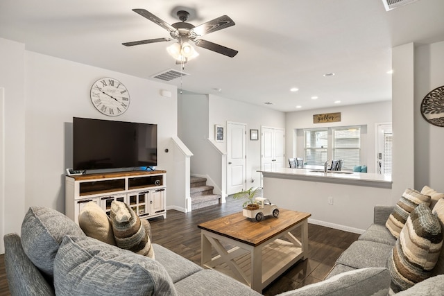 living room featuring dark wood-type flooring and ceiling fan