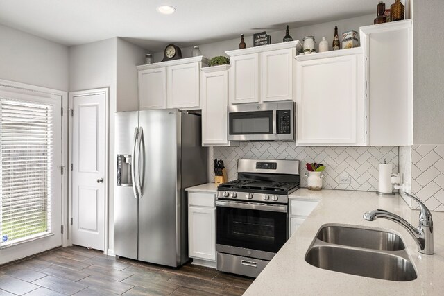 kitchen with white cabinets, stainless steel appliances, tasteful backsplash, and sink