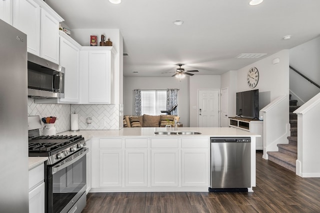 kitchen with sink, white cabinetry, appliances with stainless steel finishes, dark hardwood / wood-style floors, and kitchen peninsula