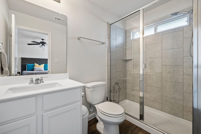 bathroom with a shower with shower door, wood-type flooring, vanity, ceiling fan, and toilet