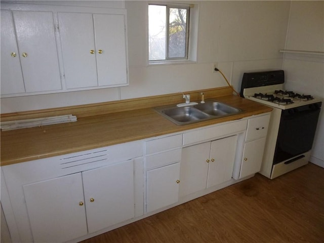 7403 Guadalupe St, Austin, TX 78752 - kitchen with gas range oven, a sink, white cabinets, wood finished floors, and light countertops