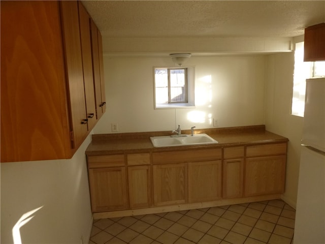 kitchen featuring light tile patterned floors, a textured ceiling, sink, and white fridge