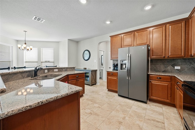 kitchen featuring a chandelier, stainless steel refrigerator with ice dispenser, sink, and a textured ceiling