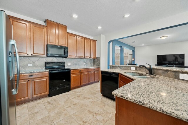 kitchen with sink, black appliances, light stone countertops, a textured ceiling, and decorative backsplash