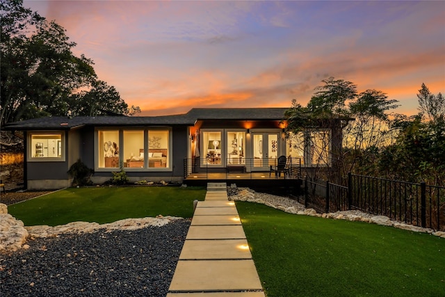 back house at dusk featuring a lawn