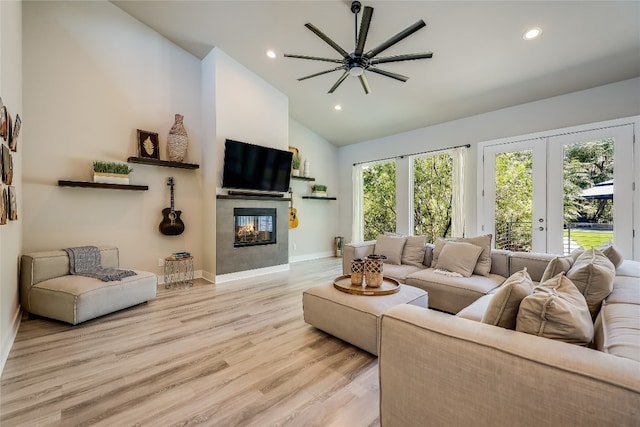 living room with french doors, vaulted ceiling, light hardwood / wood-style flooring, ceiling fan, and a fireplace