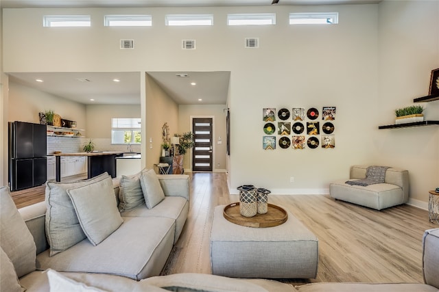 living room with light hardwood / wood-style floors and a high ceiling