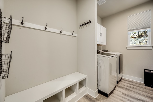 laundry room featuring cabinets, light wood-type flooring, and washing machine and dryer