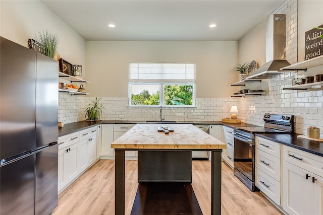 kitchen with backsplash, white cabinets, wall chimney range hood, and appliances with stainless steel finishes