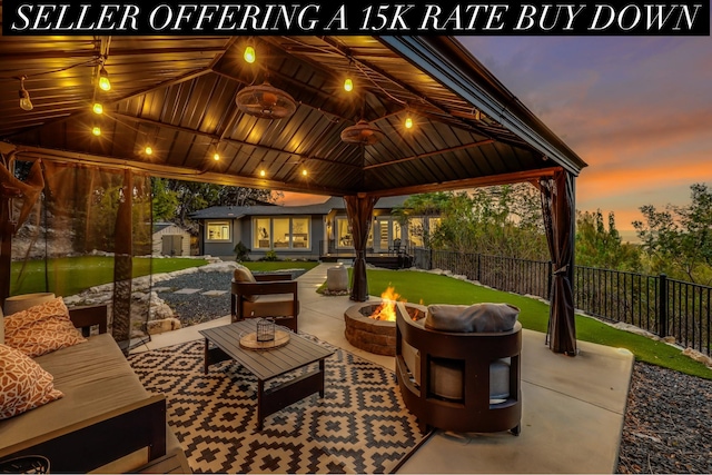 patio terrace at dusk featuring a gazebo, an outdoor living space with a fire pit, and an outdoor structure