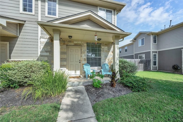 view of exterior entry with a porch and a lawn