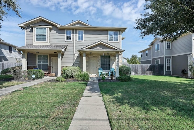 view of front facade with covered porch, a front yard, and fence