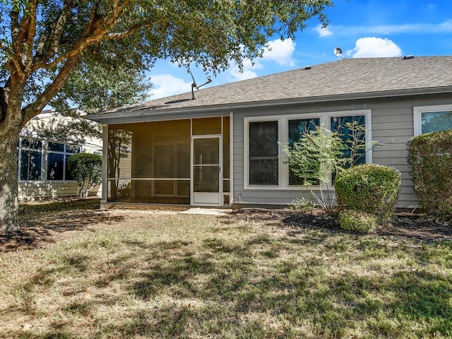 rear view of property with a lawn and a sunroom