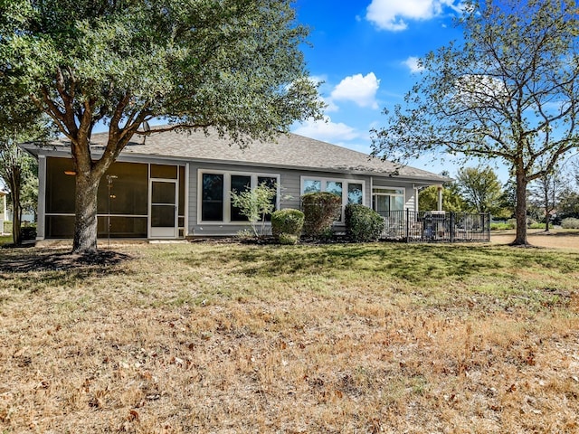 back of house featuring a lawn and a sunroom