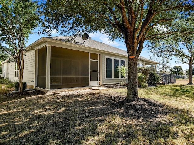 rear view of house featuring a sunroom and a lawn