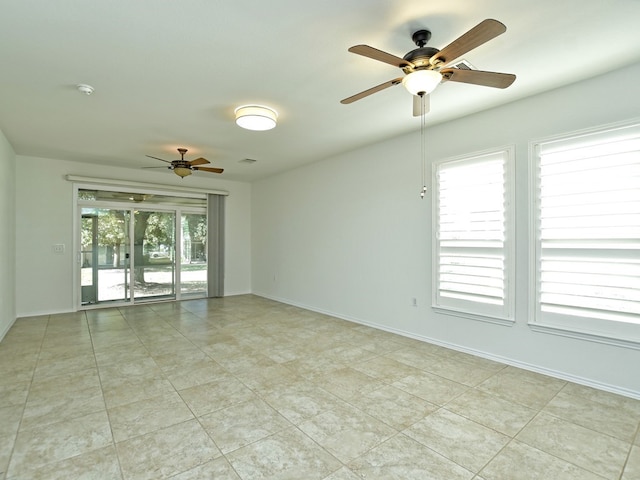 tiled empty room with ceiling fan and plenty of natural light