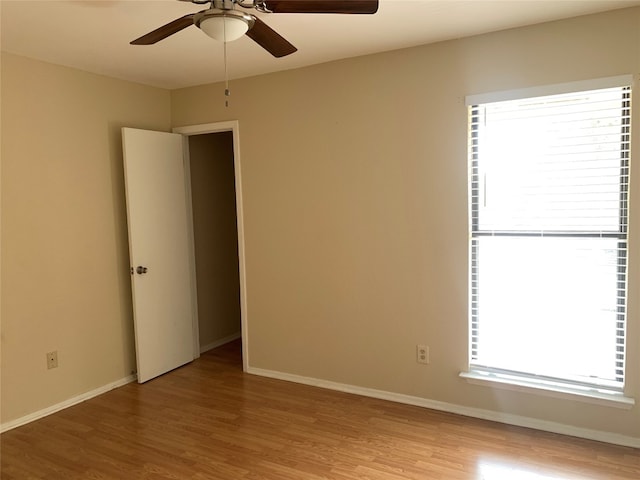 empty room with ceiling fan, a healthy amount of sunlight, and light hardwood / wood-style flooring